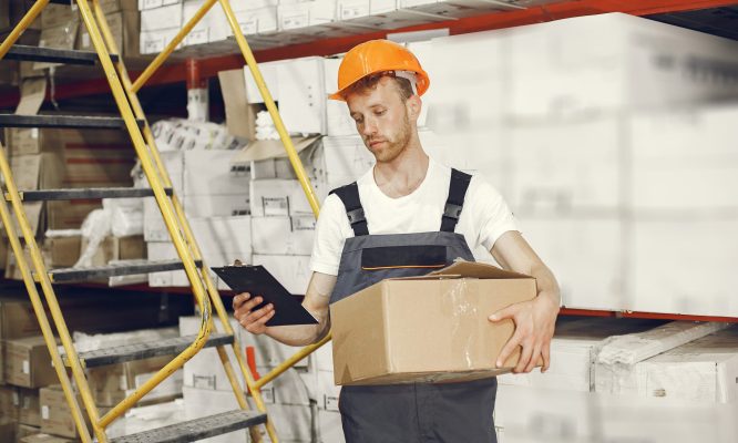 Industrial worker indoors in factory. Young technician with orange hard hat.