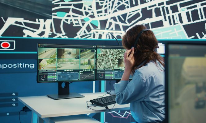 Woman call center operator guiding delivery truck drivers on different routes to avoid traffic and help with express shipment. Agency uses surveillance CCTV video and gps tracking. Camera B.